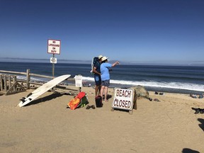 Two people look out at the shore after a reported shark attack at Newcomb Hollow Beach in Wellfleet, Mass, on Saturday, Sept. 15, 2018.