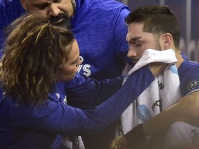 Toronto Blue Jays trainer Nikki Huffman treats Blue Jays right fielder Randal Grichuk after he collided with a security guard in foul territory on Sept. 9, 2018. (FRANK GUNN/The Canadian Press)