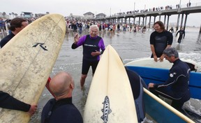 In this Oct. 3, 2010, file photo, Rev. Christian Mondor, offers a prayer to surfers during the Blessing of the Waves ceremony at the pier in Huntington Beach, Calif. California Gov. (AP Photo/Richard Vogel)