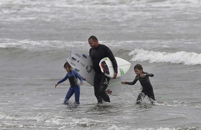 Surfing coach Justin Caron, centre, walks out of the water with two students after a lesson at Ocean Beach in San Francisco, Monday, Aug. 20, 2018. (AP Photo/Jeff Chiu)
