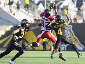 Stampeders’ Juwan Brescacin makes the catch between Richard Leonard and Mike Daly of the Ticats yesterday.  Peter Power/CP