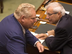Ontario Premier Doug Ford (left) speaks with Provincial Finance Minister Vic Fedeli as the Ontario Legislature hold a midnight session to debate a bill that would cut the size of Toronto city council from 47 representatives to 25, in Toronto on Monday, September 17, 2018. THE CANADIAN PRESS/Chris Young
