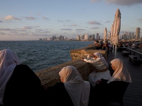 People enjoy the day on Jaffa's promenade overlooking Tel Aviv's skyline and the Mediterranean sea in Jaffa, Israel on July 26, 2018. (AP Photo/Oded Balilty)