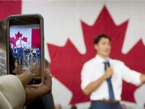 A woman films Prime Minister Justin Trudeau on her smartphone as he addresses a town hall meeting in Saskatoon, Sask., Thursday, Sept. 13, 2018.