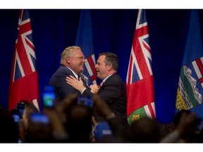 Ontario Premier Doug Ford, left, and United Conservative Leader Jason Kenney embrace on stage at an anti-carbon tax rally in Calgary, on Friday October 5, 2018.