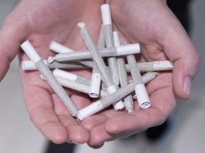 A employee holds a bunch of pre-rolled joints at Buddha Barn Craft Cannabis in Vancouver on Oct, 2, 2018.