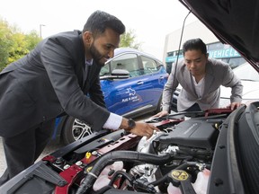 Abid Syed (left) and Mark Guinto -- both of the City of Pickering -- check under the hood of an electric car. (Craig Robertson, Toronto Sun)