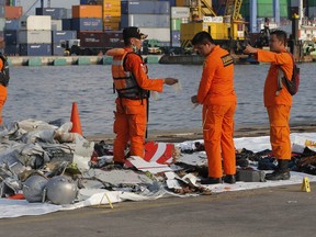 Members of Indonesian Search and Rescue Agency (BASARNAS) inspect debris recovered from near the waters where a Lion Air passenger jet is suspected to crash, at Tanjung Priok Port in Jakarta, Indonesia Monday, Oct. 29, 2018.  (AP Photo/Tatan Syuflana)