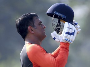 India's Mahendra Singh Dhoni prepares to wear a helmet before batting in the nets during a practice session ahead of the second one-day international cricket match between India and West Indies in Visakhapatnam, India, Oct. 23, 2018. (Aijaz Rahi/AP)