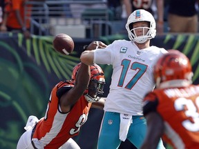 In this Oct. 7, 2018, file photo, Miami Dolphins quarterback Ryan Tannehill (17) fumbles the ball as he's hit by Cincinnati Bengals defensive end Carlos Dunlap (96) during the second half of an NFL football game, in Cincinnati. (AP Photo/Gary Landers, File)