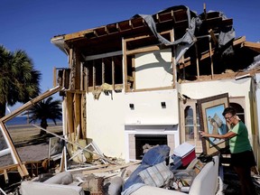 Marla Wood pulls a framed art piece out of the rubble of her damaged home from Hurricane Michael in Mexico Beach, Fla., Sunday, Oct. 14, 2018.