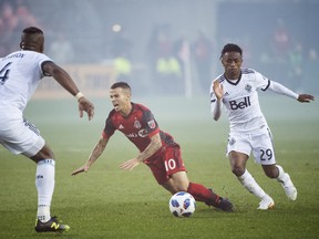 Toronto FC forward Sebastian Giovinco (10) gets tripped up by Vancouver Whitecaps forward Yordi Reyna (29) as Kendall Waston (4) look on during second-half MLS action in Toronto on Saturday, Oct. 6, 2018. (NATHAN DENETTE/THE CANADIAN PRESS)