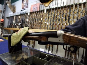An Ottawa hunting store salesperson wipes a shotgun on May 16, 2006.