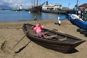Young girl handles oars in beached rowboat at the San Francisco Maritime National Historical Park, with 1895 schooner ‘C.A.Thayer’, the 1914 green-hulled ‘Eppleton Hal’l paddlewheel tug boat, and the 1890 ‘Eureka’, a ferry boat, at the Hyde Street Pier, in the background. (Ian Robertson photo)