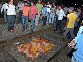 The body of a victim of a train accident lies covered in cloth on a railway track in Amritsar, India, Friday, Oct. 19, 2018.