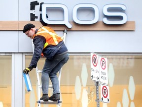 Workers remove the IQOS storefront logos as Health Canada is forcing Rothmans, Benson and Hedges company to take down signage that promotes tobacco products along Yonge St. in Toronto on Wednesday October 31, 2018. Dave Abel/Toronto Sun/Postmedia Network