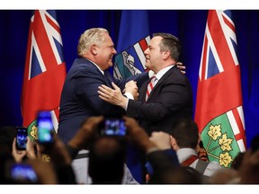 Ontario Premier Doug Ford, left, and United Conservative Leader Jason Kenney embrace on stage at an anti-carbon tax rally in Calgary, Friday, Oct. 5, 2018.