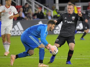 Toronto FC goalkeeper Alex Bono, left, makes a save in front of D.C. United forward Wayne Rooney during Wednesday's match in Washington. The Associated Press
