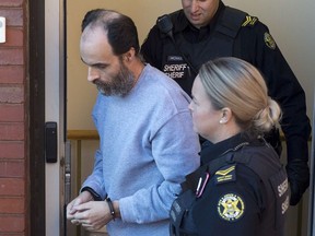 Matthew Vincent Raymond, charged with four counts of first degree murder, is escorted from provincial court in Fredericton on Monday, Oct. 22, 2018. Two city police officers were among four people who died in a shooting in a residential area on the city's north side.