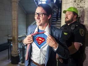 Prime Minister Justin Trudeau shows off his costume as Clark Kent, alter ego of comic book superhero Superman, as he walks through the House of Commons, in Ottawa on Tuesday, Oct. 31, 2017.