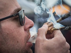 Brandon Bartelds smokes three joints at once while attending the 4-20 annual marijuana celebration, in Vancouver, B.C., on Friday April 20, 2018. (THE CANADIAN PRESS/Darryl Dyck)