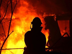 A firefighter looks on as a home is consumed by the Camp Fire on November 8, 2018 in Paradise, Calif.