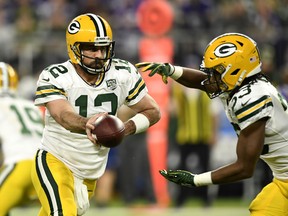 Aaron Rodgers #12 of the Green Bay Packers hands the ball off to Aaron Jones #33 in the first quarter of the game against the Minnesota Vikings at U.S. Bank Stadium on November 25, 2018 in Minneapolis, Minnesota.