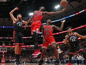 Justin Holidayof the Chicago Bulls rebounds over teammate Antonio Blakeney  and Jonas Valanciunas #17 and Malachi Richardson of the Toronto Raptors at United Center on Saturday. (Photo by Jonathan Daniel/Getty Images)