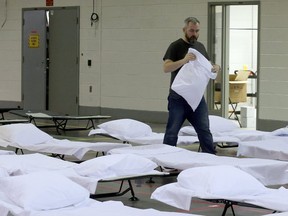 Gary Muirhead, a Homes First employee, prepares bedding at a new respite centre located at the Queen Elizabeth Building at Exhibition Place. (Dave Abel, Toronto Sun)