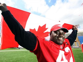 Defensive lineman Mike Labinjo mugs for a photo with a Canadian flag during Calgary Stampeders practice at McMahon Stadium on June 30, 2009. (Lyle Aspinall/Postmedia)