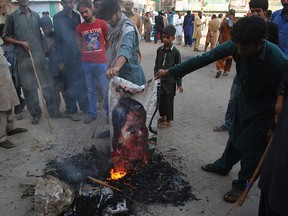 Pakistani protesters burn a poster image of Christian woman Asia Bibi, who has spent eight-years on death row accused of blasphemy and acquitted by a Supreme Court, in Hyderabad, Pakistan, Thursday, Nov. 1, 2018.