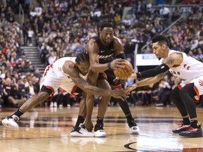 Miami Heat guard Dwyane Wade, centre, gathers a loose ball between Toronto Raptors Kawhi Leonard, left, and Danny Green during second half in Toronto on Sunday. THE CANADIAN PRESS/Chris Young