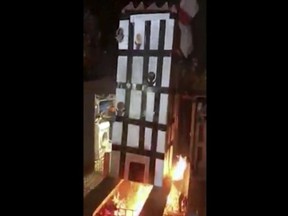 In this grab taken from video, made available on Tuesday, Nov. 6, 2018, people place a model of Grenfell Towers onto a bonfire, in London. London police have arrested five people over a video that showed a cardboard model of Grenfell Tower being burned on a bonfire -- a video that shocked the families of the 72 victims who died in the 2017 inferno that engulfed the apartment block. (UGC via AP) ORG XMIT: AMB805