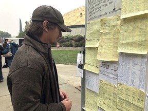 Wildfire evacuee Greg Gibson looks for information about his missing neighbors at The Neighborhood Church in Chico, Calif., on Tuesday, Nov. 13, 2018. The fire exploded so quickly, Gibson said, that he first noticed the bottom of a shed burning about one-quarter of a mile from his house and by the time he reached the home he shares with an elderly woman, the fire was on all sides. He helped his 79-year-old roommate into her car and they fled.