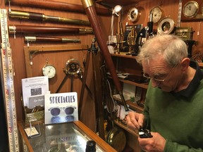 Erskine holds a Curta pocket calculator at his Portobello Road stall. (Lance Hornby/Toronto Sun)