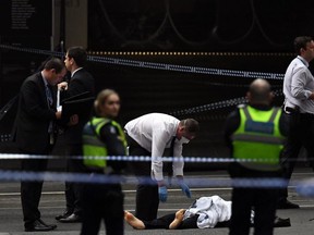 Detectives stand over the body of a man killed in the terrorist attack in Melbourne on Friday.