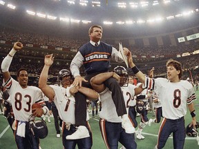 In this Jan. 26, 1986, file photo, Bears head coach Mike Ditka is carried off the field by Steve McMichael, left, and William Perry after the Bears defeated the  Patriots in Super Bowl XX in New Orleans. Willie Gault (83) and Maury Buford (8) join the celebration.