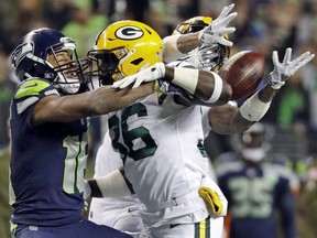 Green Bay Packers defensive back Raven Greene, center, and cornerback Jaire Alexander, right, break up a pass intended for Seattle Seahawks wide receiver Tyler Lockett during the first half of an NFL football game, Thursday, Nov. 15, 2018, in Seattle. Greene was flagged for pass interference on the play. The Seahawks won 27-24.