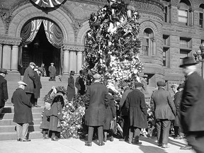 Prior to the construction of the present Cenotaph in front of Toronto’s Old City Hall, citizens placed flowers and wreaths at a temporary wooden “cenotaph” located where the present cenotaph would be erected in 1925. This photo was taken prior to the 1922 Armistice Day gathering and is from the City of Toronto Archives. Interestingly, the idea of erecting a proper and permanent cenotaph in front of the main entrance to City Hall had actually been proposed by Mayor Tommy Church two years earlier. It wasn’t until July 24, 1924, that the city’s Board of Control agreed that a permanent war memorial be erected and then selected the design submitted by the Toronto architectural firm of Ferguson and Pomphrey. The estimated budget was set at $25,000. The architects’ fee would be $2,500 with $17,800 the amount tendered by McIntosh Granite of Toronto, the supplier of the grey granite stone from Stanstead, Que. Imagine, a city project that actually came in under budget. (City of Toronto Archives)