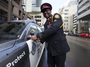 Toronto Police Chief Mark Saunders ties a red ribbon onto a Toronto police cruiser, marking the 31st anniversary of MADD Canada's red ribbon campaign (Stan Behal/Toronto Sun)