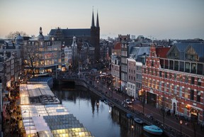 Flower stalls, left, float illuminated on a canal at the Bloemenmarkt as the Kalverton retail mall sits on the opposite bank in Amsterdam in 2013. (Bloomberg photo by Jasper Juinen)