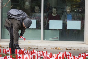 Smiles from inside as a volunteer places a few of the 47,500 Canadian flags on the lawns outside of Sunnybrook Veterans Centre on the grounds at Sunnybrook Health Sciences Centre in Toronto, Ont. on Saturday November 10, 2018. There were 100 flags for each of the 475 veterans that live there. Ernest Doroszuk/Toronto Sun/Postmedia
