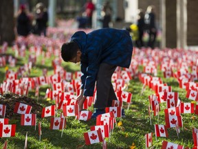 Marco Ho, 12, places a few of the 47,500 Canadian flags on the lawns outside of Sunnybrook Veterans Centre on the grounds at Sunnybrook Health Sciences Centre in Toronto, Ont. on Saturday November 10, 2018. There were 100 flags for each of the 475 veterans that live there. Ernest Doroszuk/Toronto Sun/Postmedia