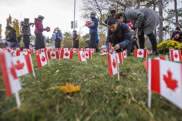 Austin Hua, 15, places a few of the 47,500 Canadian flags on the lawns outside of Sunnybrook Veterans Centre on the grounds at Sunnybrook Health Sciences Centre in Toronto, Ont. on Saturday November 10, 2018. There were 100 flags for each of the 475 veterans that live there. Ernest Doroszuk/Toronto Sun/Postmedia