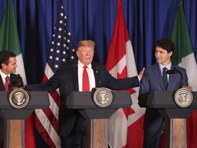 President Donald Trump, center, reaches out to Mexico's President Enrique Pena Nieto, left, and Canada's Prime Minister Justin Trudeau as they prepare to sign a new United States-Mexico-Canada Agreement that is replacing the NAFTA trade deal, during a ceremony at a hotel before the start of the G20 summit in Buenos Aires, Argentina, Friday, Nov. 30, 2018. (AP Photo/Martin Mejia)