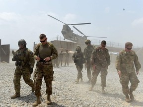 In this file photo taken on Aug. 12, 2015, U.S. army soldiers in Afghanistan walk as a NATO helicopter flies overhead at coalition force Forward Operating Base (FOB) Connelly in the Khogyani district in the eastern province of Nangarhar.
