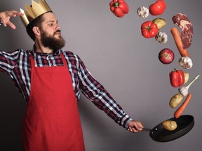 Cooking man concept, king of kitchen,bearded man in checked shirt, drop up meat and vegetables from a pan, studio shot on gray background