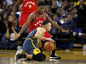 Stephen Curry of the Golden State Warriors dribbles on his knees while being guarded by Kyle Lowry of the Toronto Raptors at ORACLE Arena on December 12, 2018 in Oakland. (Ezra Shaw/Getty Images)