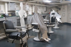 Silhouette figures represent barber and sailors getting hair trims in the barbershop during the Second World War aboard battleship USS North Carolina. (Ian S. Robertson)
