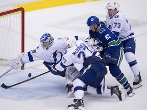 Tampa Bay Lightning goaltender Andrei Vasilevskiy (88) tries to stop the puck as Lightning Ryan McDonagh and Adam Erne (73) and Vancouver Canucks center Jay Beagle (83) look on in Vancouver Tuesday, Dec. 18, 2018. (Jonathan Hayward/The Canadian Press via AP)